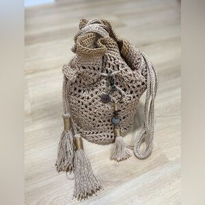 The Sak cream and gold crochet bag with tassels, featuring a boho style